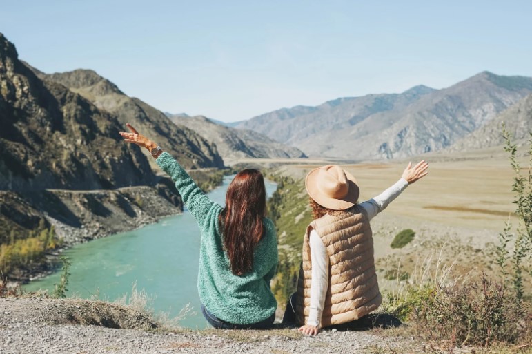 Dwie kobiety siedzą na ziemi i patrzą na góry